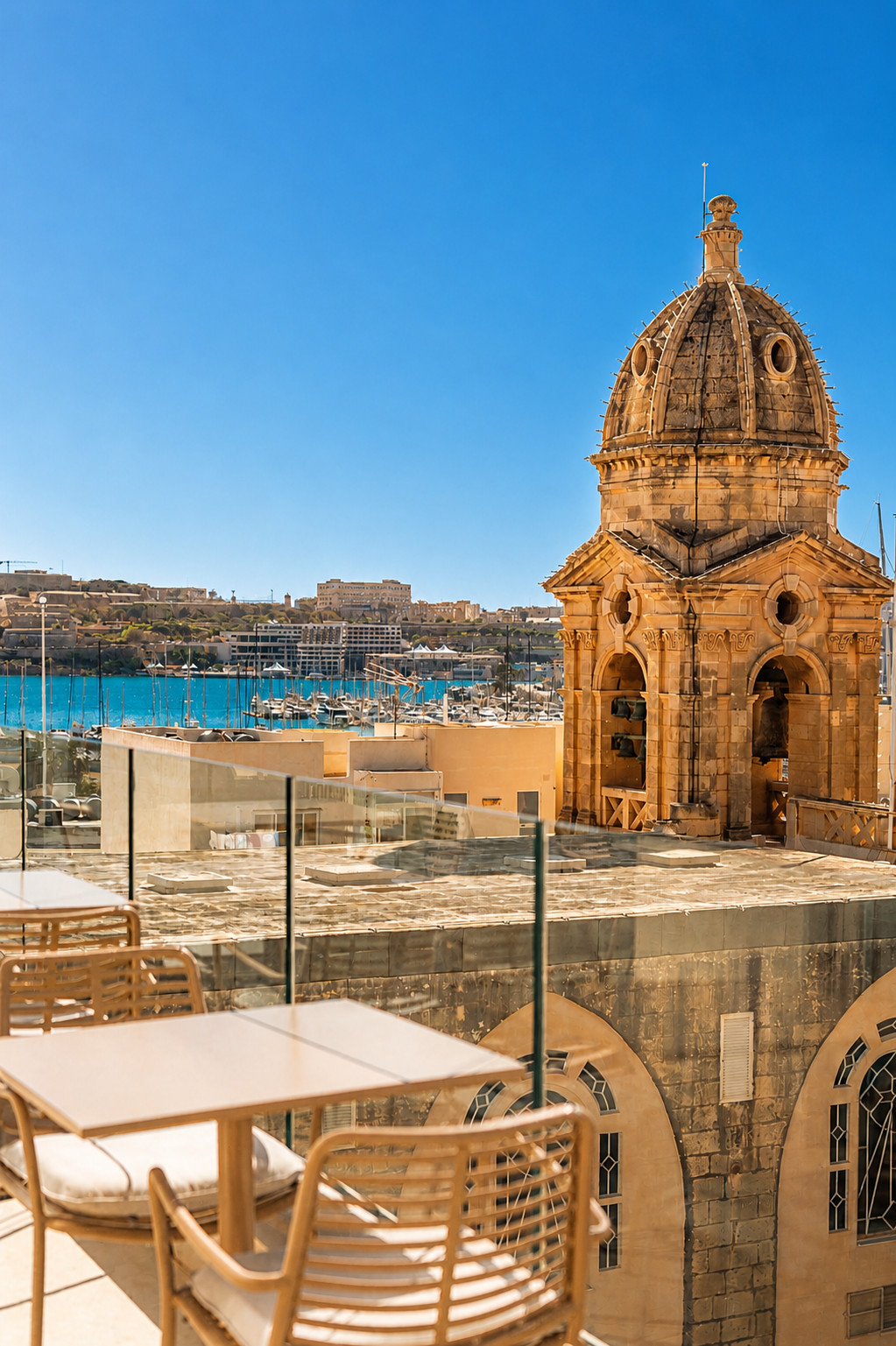 View from Boeme hotel rooftop terrace with historic church architecture and harbour views in Malta